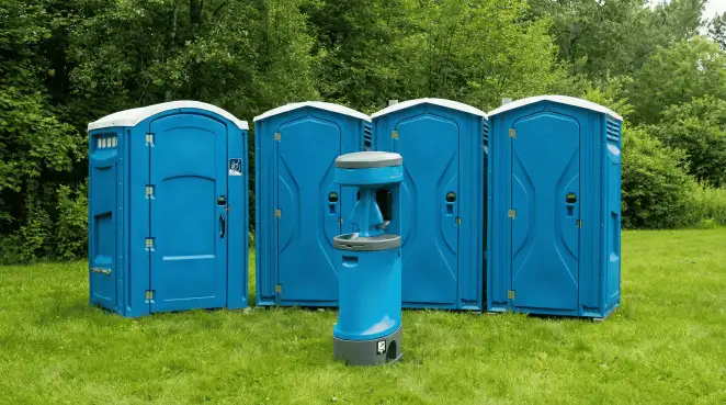 Four blue portable toilets and a matching hand washing station on grass near trees, a common sight at local outdoor events in Henderson, NV